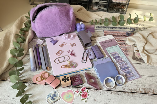 Collection of stationery items including a purple bag, scissors, and decorative paper.
